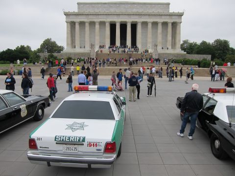 1991 Ford LTD Crown Victoria - green-and-white Sheriff cruiser parked among other police cars on the plaza facing the Lincoln Memorial and crowds.