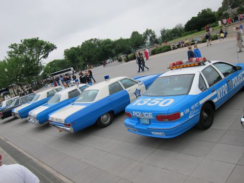 1991 Ford LTD Crown Victoria - row of blue-and-white NYPD police cruisers parked at an angle on a plaza, the nearest marked 1350.
