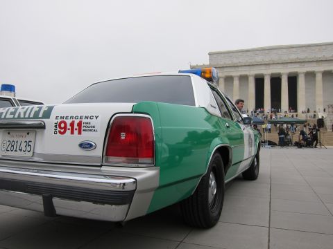 1991 Ford LTD Crown Victoria - Rear quarter of a green-and-white Ford Sheriff cruiser with EMERGENCY 911 markings parked near the Lincoln Memorial.