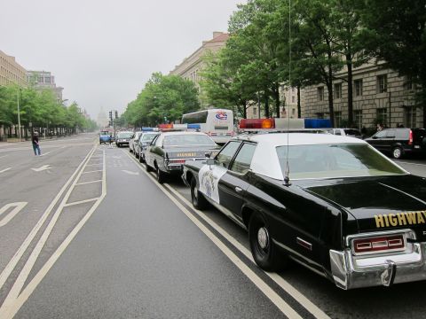 1991 Ford LTD Crown Victoria - Black-and-white Highway Patrol cruisers lined along a city street leading toward the distant US Capitol dome.