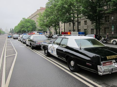 1991 Ford LTD Crown Victoria - line of classic black-and-white California Highway Patrol-marked sedans parked along a tree-lined city street near the U.S. Capitol.