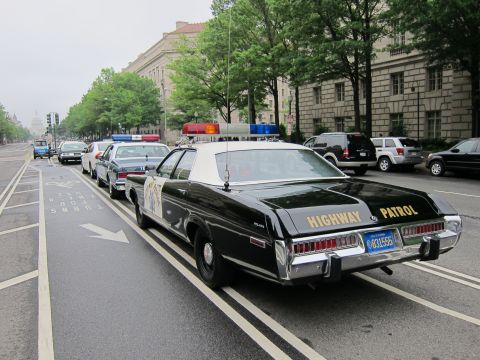 1991 Ford LTD Crown Victoria - Rear three-quarter view of a black-and-white Highway Patrol sedan with a California license plate, parked in a bike lane on a city avenue.