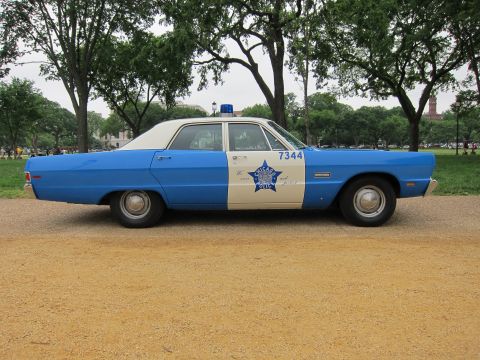 1991 Ford LTD Crown Victoria - blue-and-white vintage Chicago Police sedan numbered 7344 with a star badge and roof beacon, shown in side profile in a park.