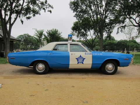 1991 Ford LTD Crown Victoria - blue-and-white Chicago Police sedan numbered 8208 with a roof beacon and star badge, shown in side profile in a park.