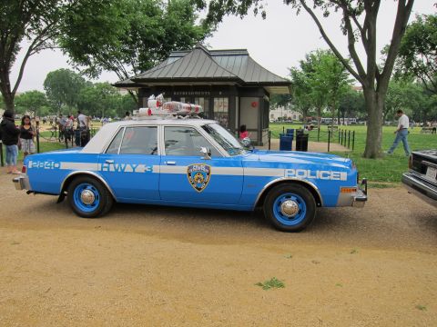 1991 Ford LTD Crown Victoria - blue-and-white NYPD highway patrol sedan numbered 2840 with roof lights and 'Police' lettering, in side profile near a park pavilion.