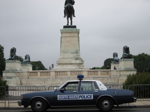 1991 Ford LTD Crown Victoria - dark blue North Haven Police sedan parked in front of a stone monument topped by an equestrian statue flanked by lions.