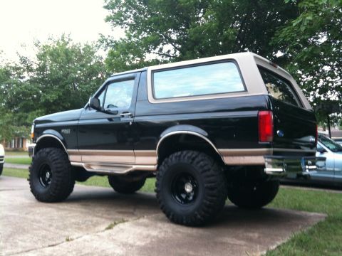 1996 Ford Bronco - Rear 3/4 view of a lifted 1996 Ford Bronco with black body and tan trim.