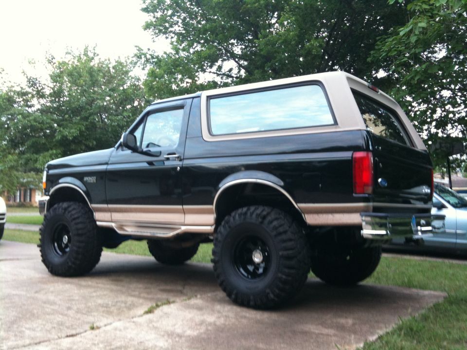 1996 Ford Bronco, black with tan trim, lifted with large tires, parked on driveway
