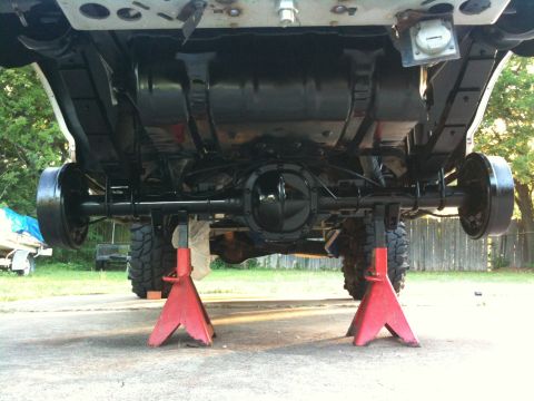 1996 Ford Bronco - The underside of a vehicle is elevated on red jack stands, revealing its mechanical components.