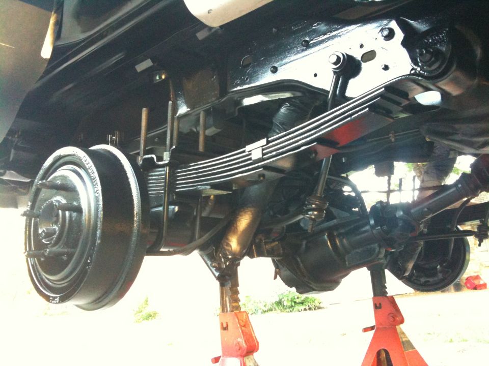 Rear axle and leaf springs on jack stands, black painted components, drum brake visible