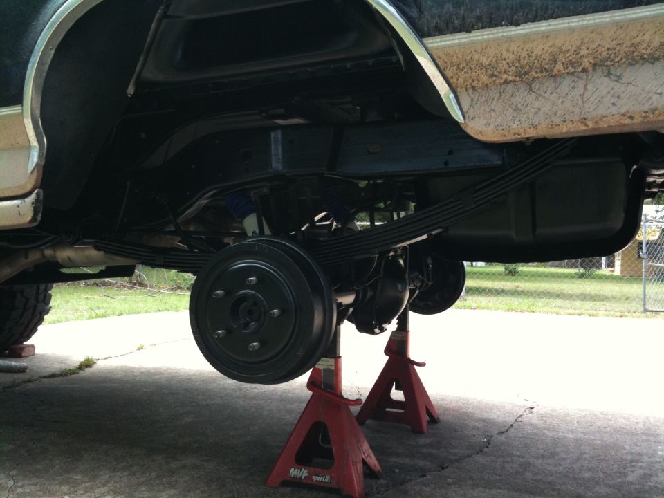 Rear suspension and undercarriage of a vehicle on jack stands, showing leaf springs and drum brakes