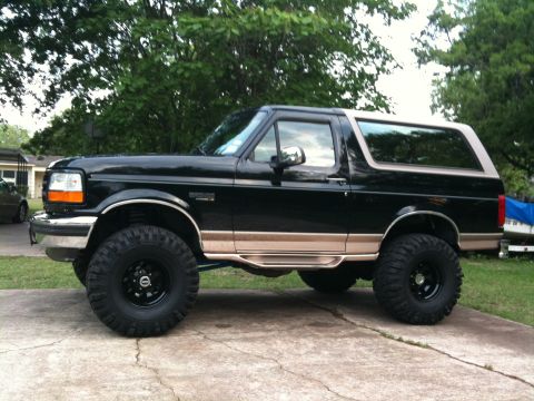 1996 Ford Bronco - This lifted 1996 Ford Bronco is presented in a side profile view, its black paint with tan accents.