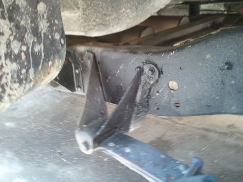 1978 Ford Bronco - Underside view of vehicle frame and suspension components, with a partial tire in the frame.