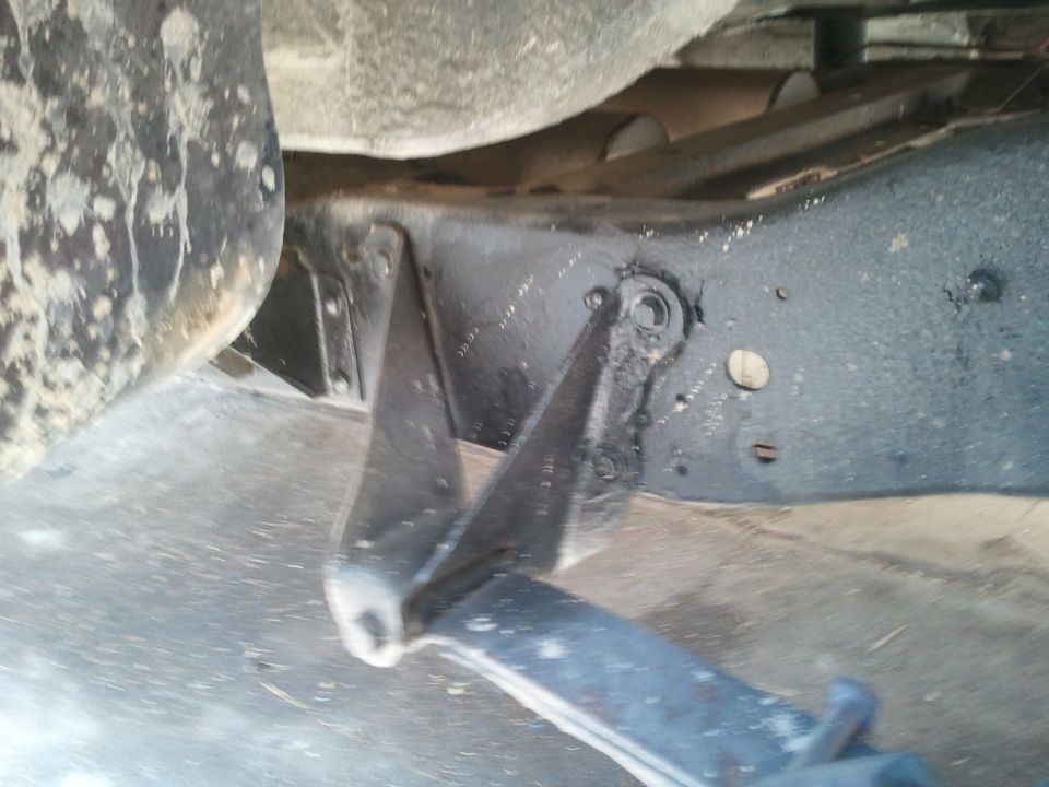 Close-up of vehicle frame with suspension components and tire visible. Watermark says SUPERMOTORS.NET