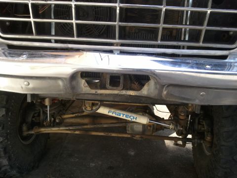 1978 Ford Bronco - Close-up view of the front suspension and bumper assembly, a Fabtech shock absorber and tow hitch receiver.