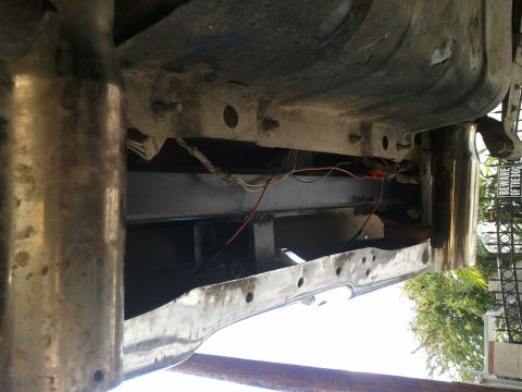 1978 Ford Bronco - The underside of a vehicle shows its frame, exhaust, and wiring, with a 'Beware of the Dog' sign in the background.