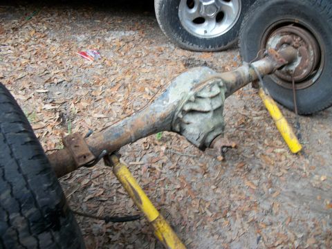 1994 Ford Explorer - A rusty rear axle assembly with yellow shocks and tires is visible, with another vehicle's wheel in the background.