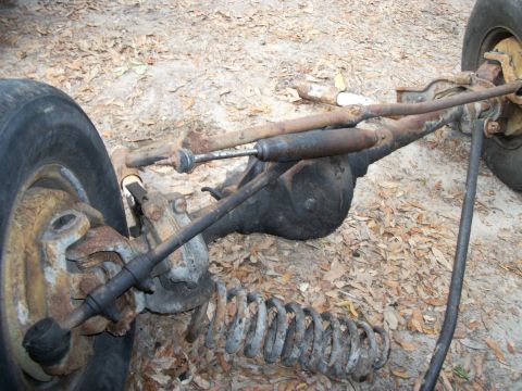 1994 Ford Explorer - Close-up view of a vehicle's front axle assembly, including suspension and steering components, lying on the ground.