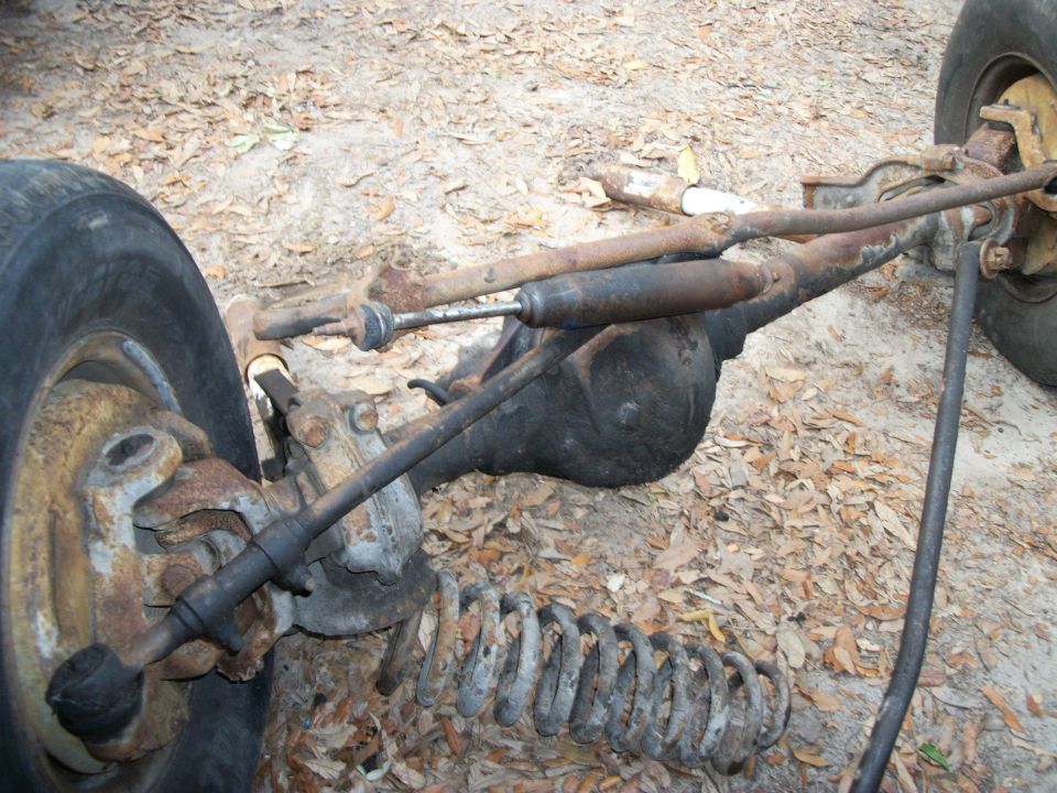 Front axle assembly with coil spring and steering linkage