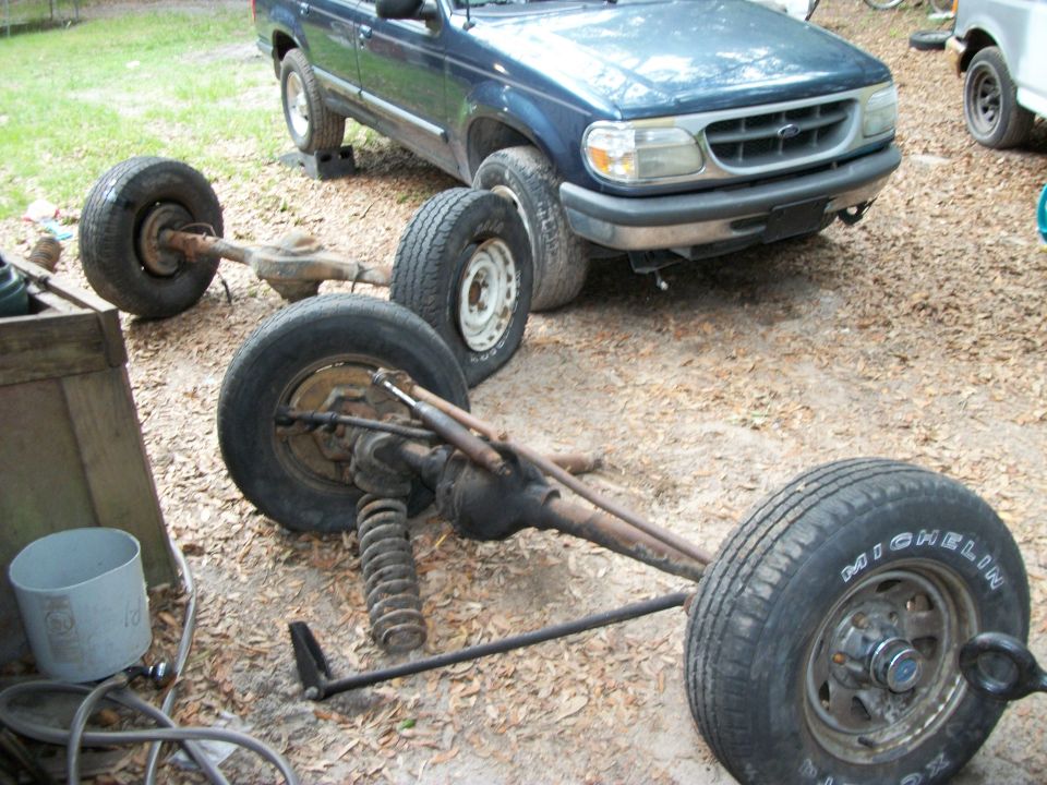 Blue 1995 Ford Explorer with its rear axle removed and lying on the ground