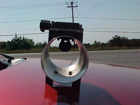 1995 Ford Mustang - A close-up of a chrome exhaust pipe on a red vehicle's hood.