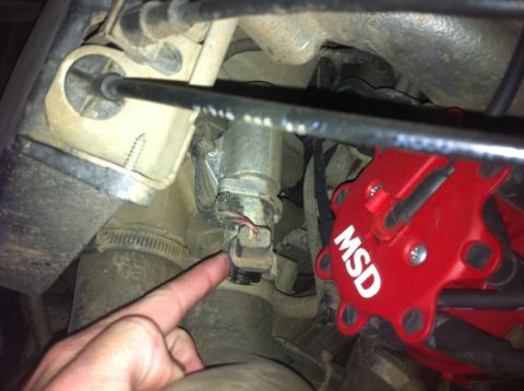 1990 Ford Bronco - A finger points to a sensor near a red MSD distributor in a vehicle's engine compartment.