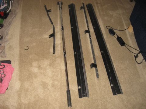 1990 Ford Bronco - Several disassembled car parts, including metal strips and a rod, are arranged on a carpeted floor.