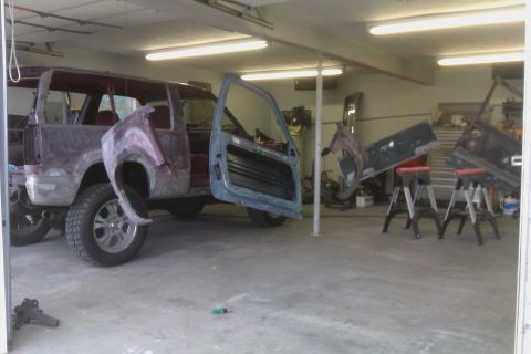 1994 Chevrolet Blazer - An SUV body, stripped down and in primer, sits in a garage with its doors removed.