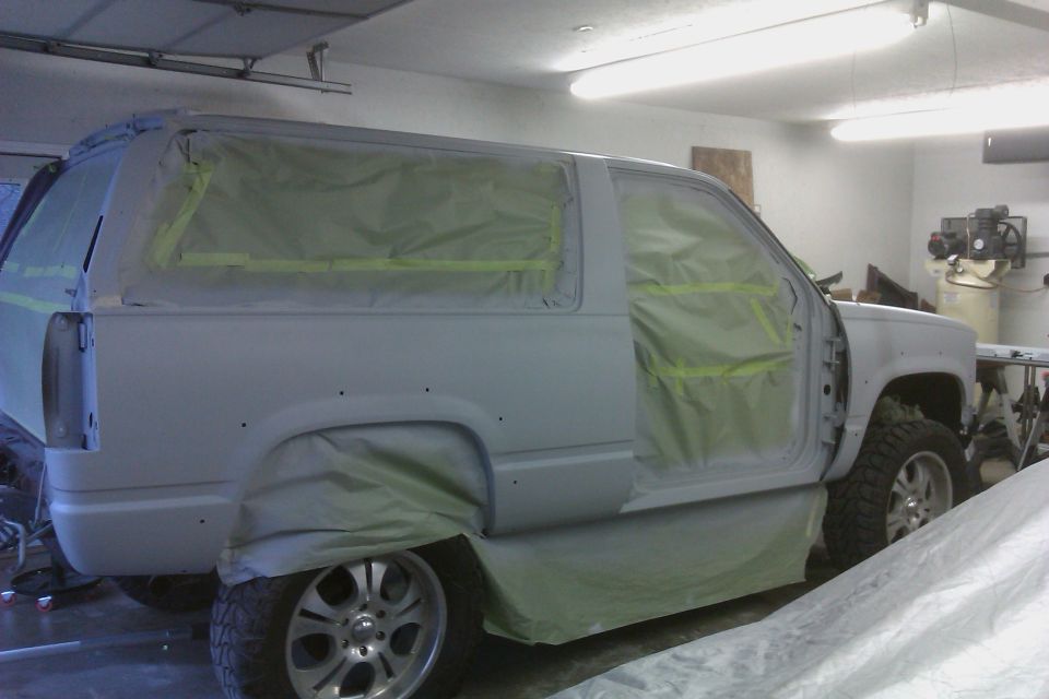 SUV covered in masking paper and tape, ready for paint. Door is open