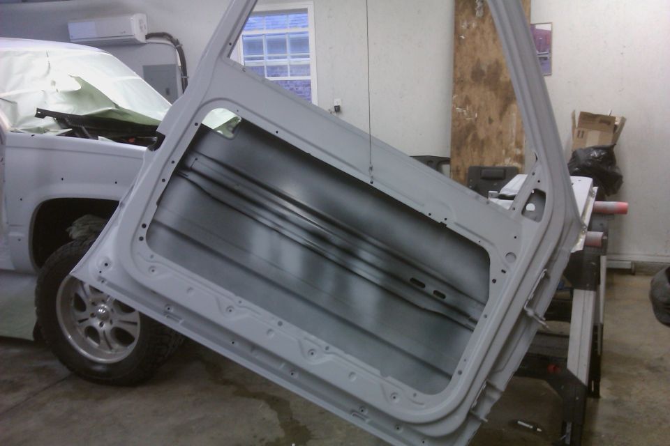 Vehicle door open, showing interior. Part of truck body visible, covered in white sheeting