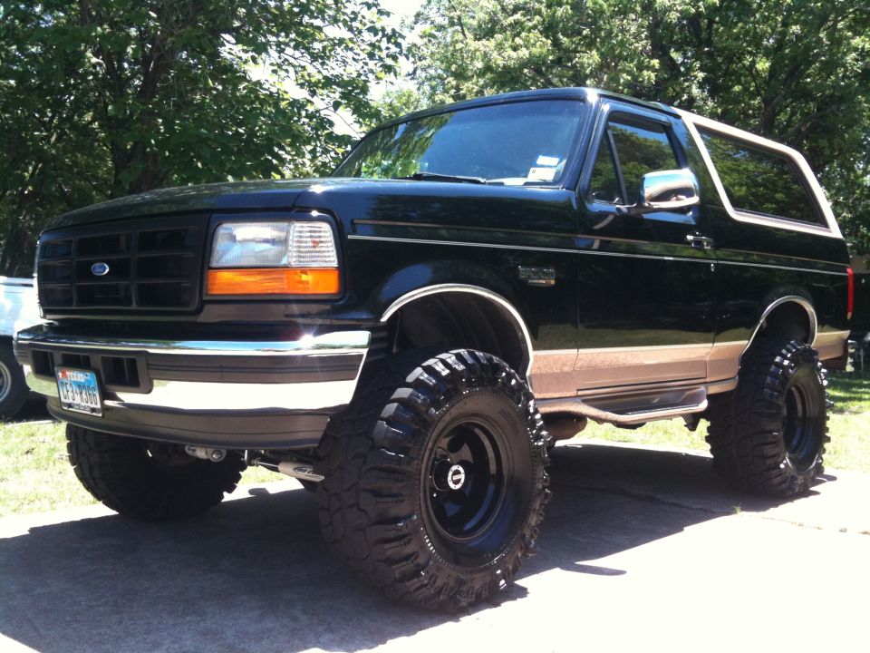 1996 Ford Bronco lifted with large off-road tires, black and tan paint