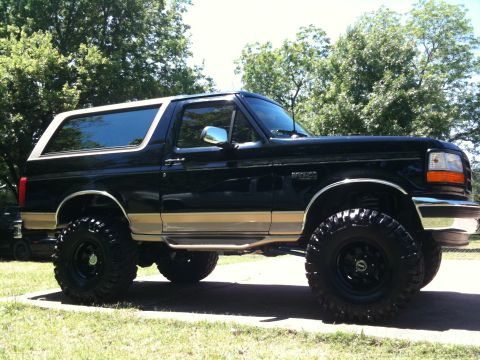 1996 Ford Bronco - This black 1996 Ford Bronco features tan trim and a lifted suspension, presented in a 3/4 front view.
