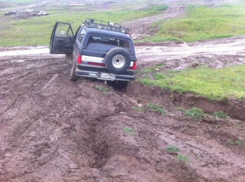 1990 Ford Bronco - This 1990 Ford Bronco is stuck in a muddy rut, with its driver's door open.