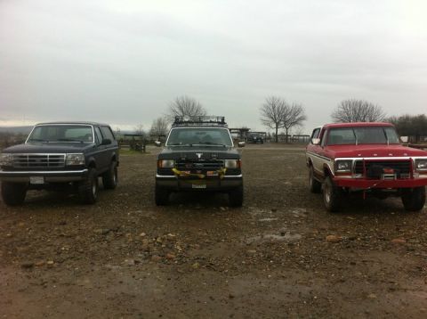 1990 Ford Bronco - Three Ford Broncos are parked in an outdoor lot on a cloudy day.