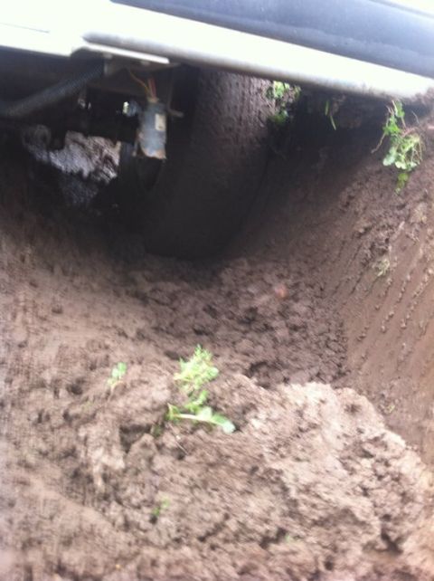 1990 Ford Bronco - A vehicle is stuck in thick mud, with its undercarriage and tire partially visible.