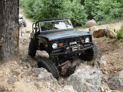 1967 Ford Mustang - A modified Ford Bronco tackles a challenging rocky terrain on an off-road trail.