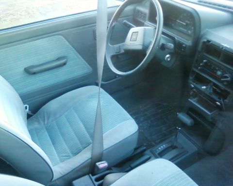 1991 Ford Festiva - Interior view of a car showing the driver's seat, dashboard, and center console.