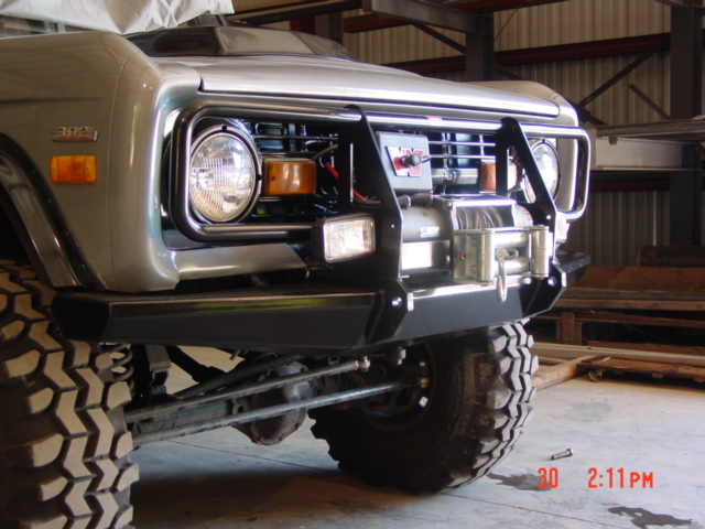 Lifted 4x4 front end with black winch bumper, brush guard and Warn winch inside a shop