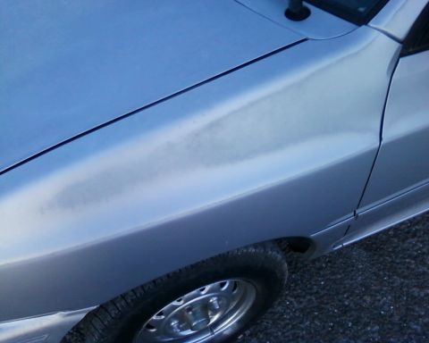 1991 Ford Festiva - Close-up of a silver car's fender and wheel, showing part of the side panel.