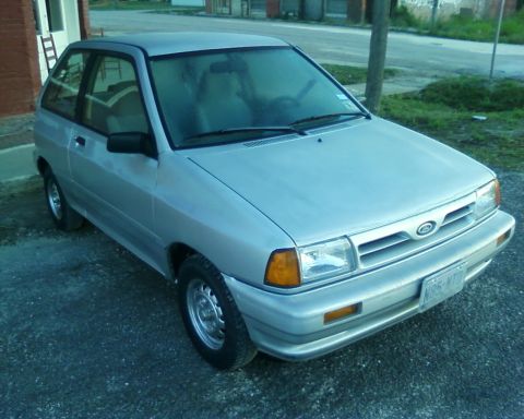 1991 Ford Festiva - This silver hatchback has a distinctive grille and headlight design.