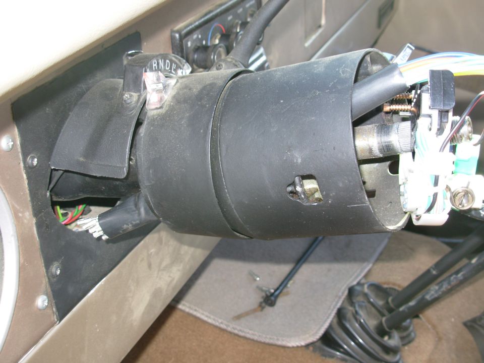 Steering column wrapped in black tape under the dash with wiring exposed