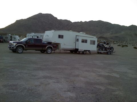 2011 Ford F-250 - A Ford F-250 tows a large fifth-wheel trailer and a UTV trailer in a dry, mountainous area.