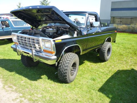 1995 Ford Bronco - A black Ford Bronco is displayed with its hood open, showing the engine and lifted suspension.