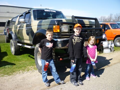 1995 Ford Bronco - Camouflaged Ford Bronco with lifted suspension and bull bar, posing with three children.