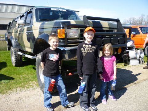 1995 Ford Bronco - Three children pose with a heavily modified SUV a custom camouflage paint job and off-road tires.