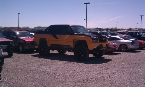 1994 Ford Bronco - A lifted pickup truck with a two-tone paint job is parked in a lot with other vehicles.
