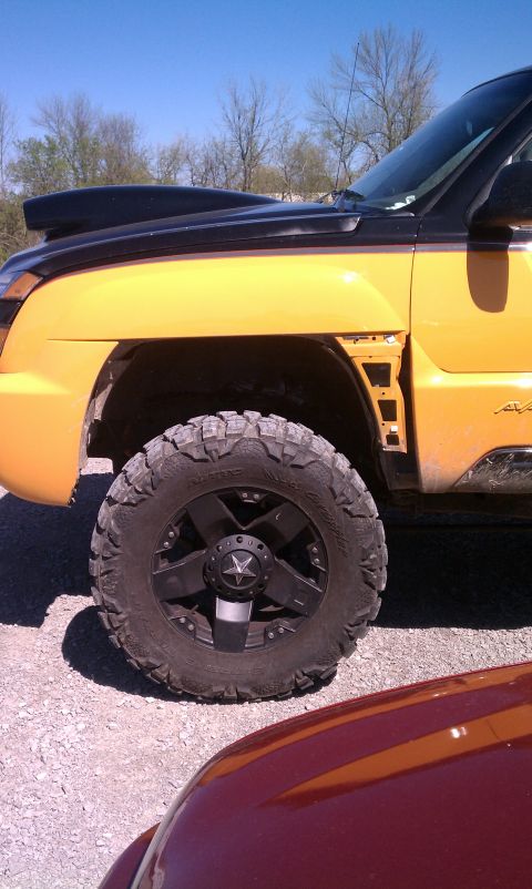 1994 Ford Bronco - This yellow truck features a black hood scoop and custom black wheels with a star emblem on the center cap.