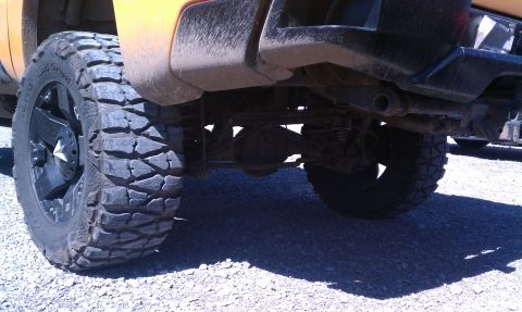 1994 Ford Bronco - The underside of a lifted truck is shown, focusing on the rear axle and aggressive off-road tires.