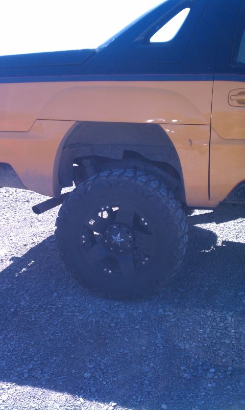 1994 Ford Bronco - A yellow SUV with a black roof and large off-road tires is parked on a gravel surface.