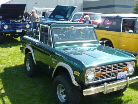 1995 Ford Bronco - Several Ford Broncos are gathered together on a sunny day, with one green Bronco in the foreground.